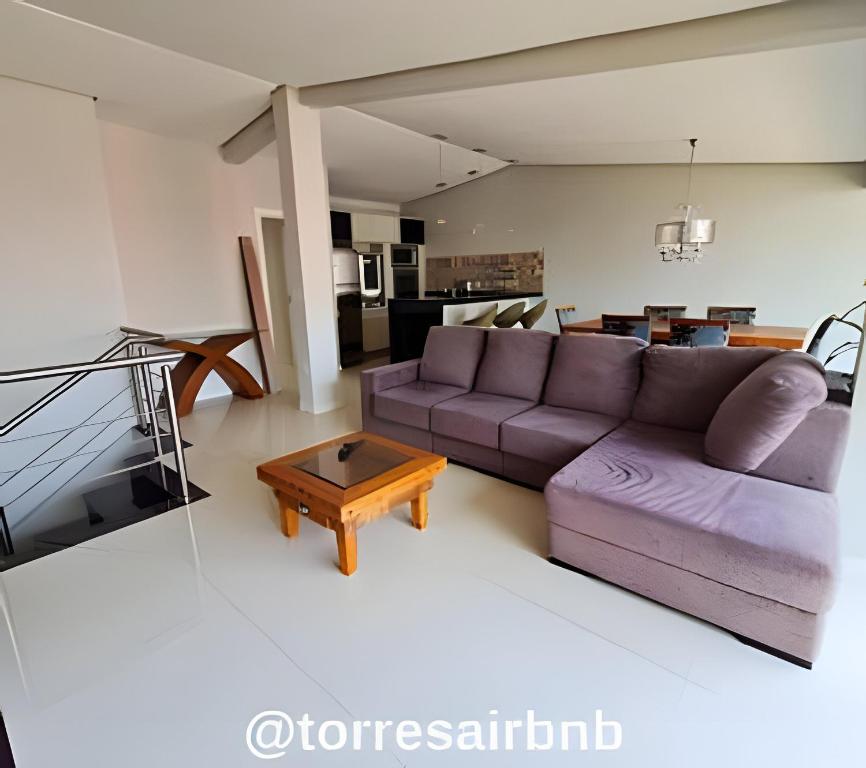 sala de estar con sofá púrpura y mesa en Cobertura a poucos metros do mar, en Torres