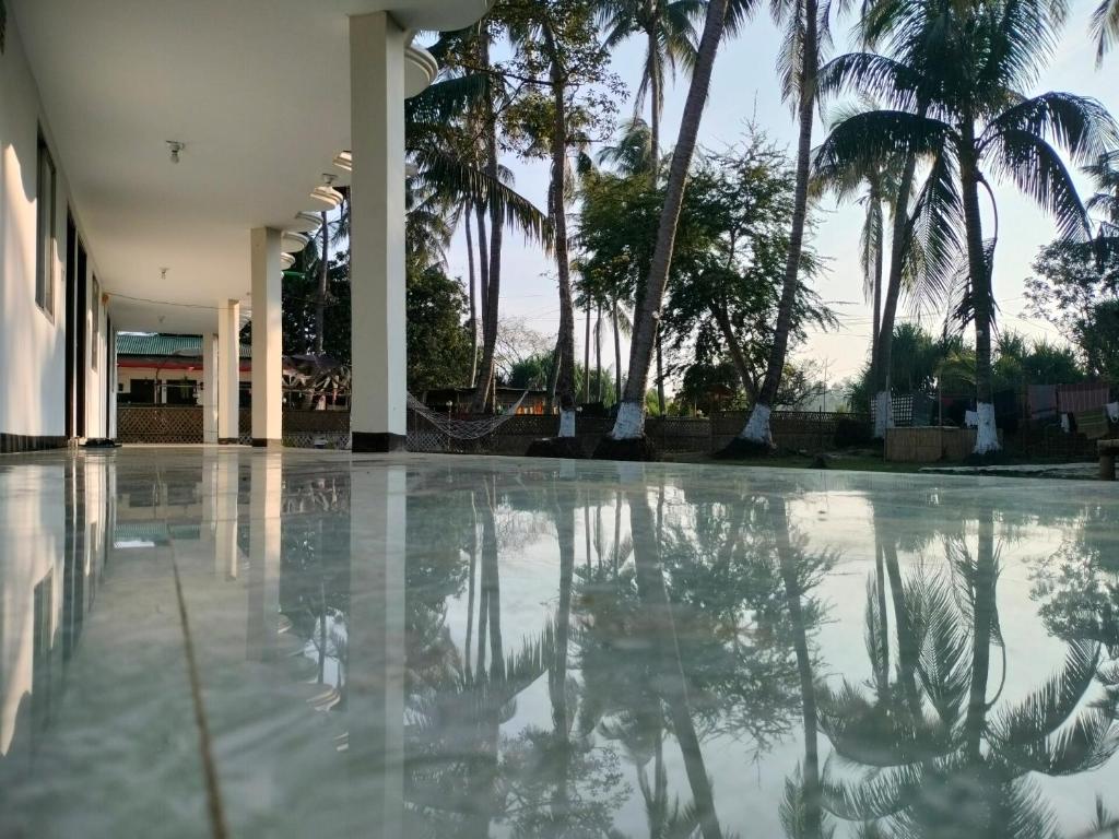 an empty swimming pool with palm trees in the background at Surjasto Resort in Jaliapāra