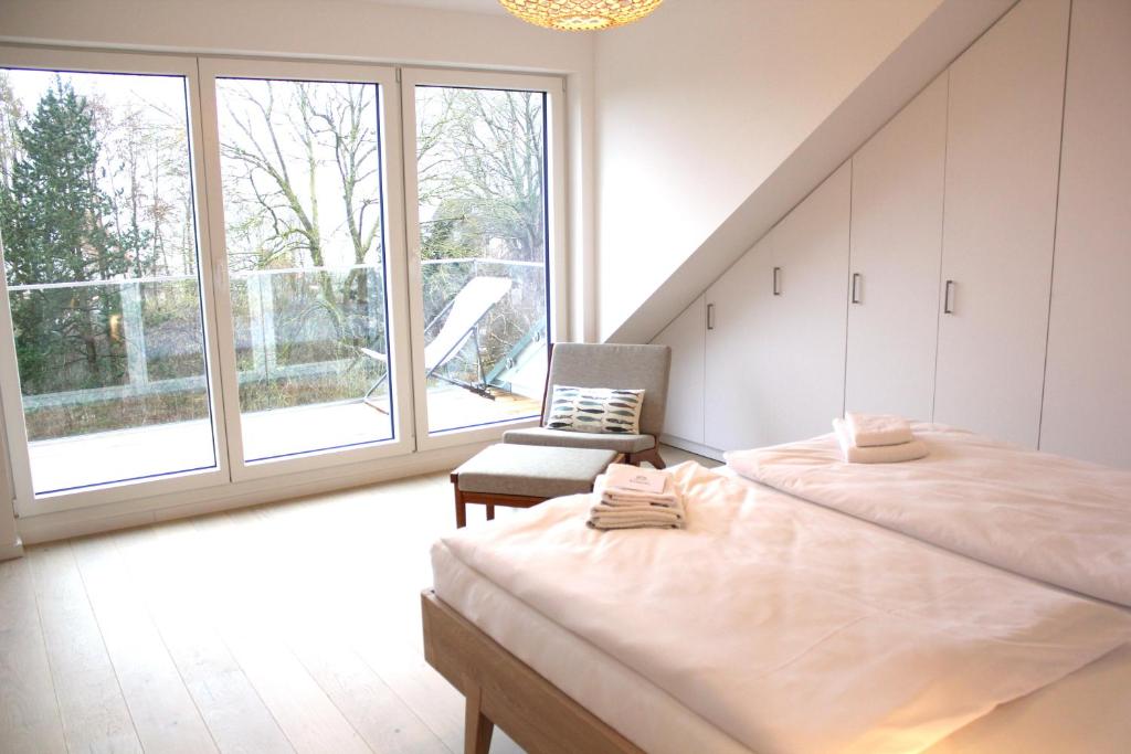 a bedroom with a bed and a chair and windows at strand Frische in Neustadt in Holstein