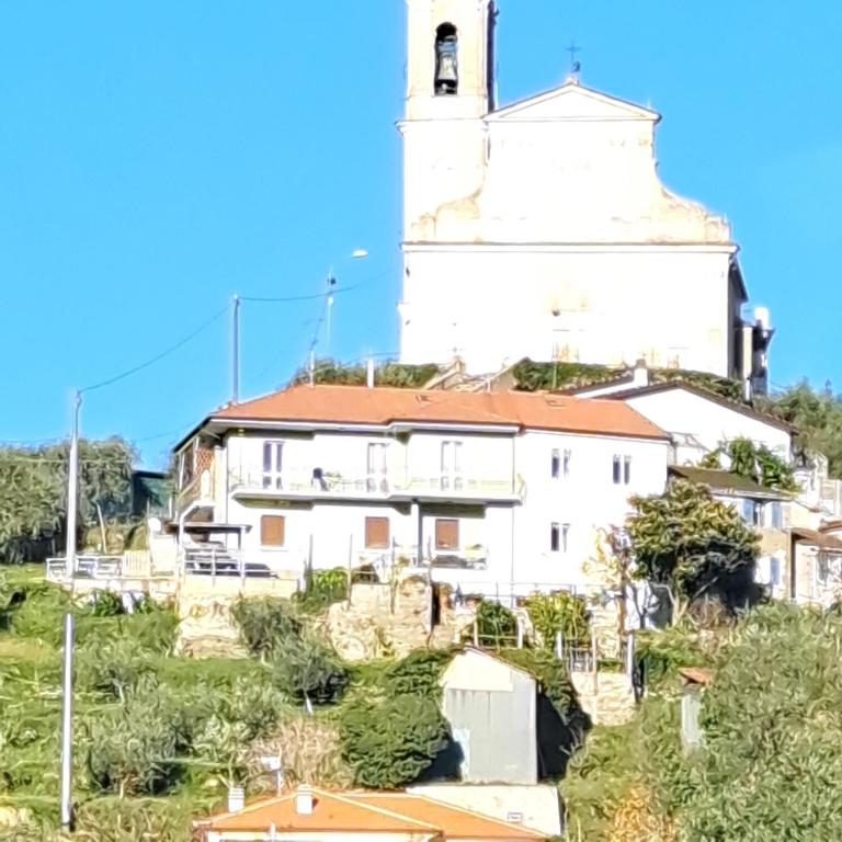 a white building with a clock tower on a hill at IL SOLE DI AURORA in Carasco