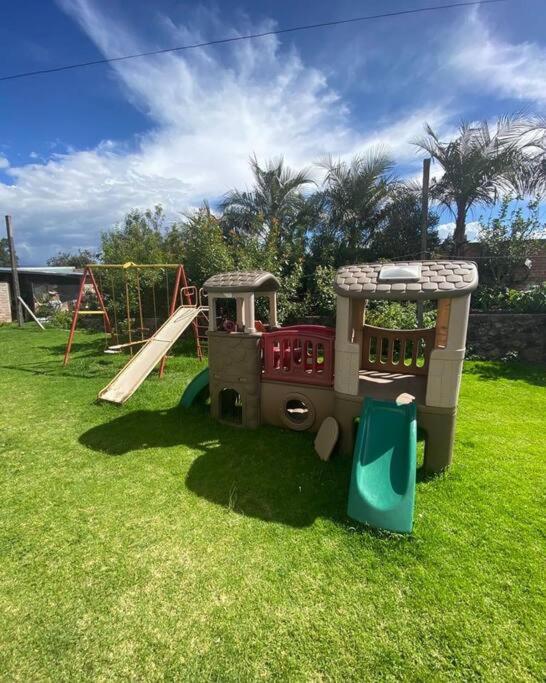 un tren de juguete en un patio de recreo en el césped en Cabaña de campo Guano Ecuador, en Guano