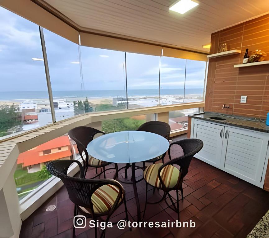 a kitchen with a table and chairs and a view of the ocean at Apartamento com vista para o mar in Torres