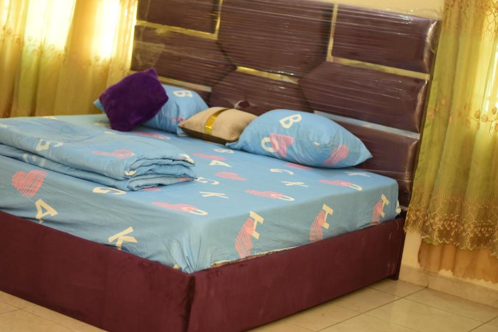 un letto con piumone e cuscini blu sopra di Royal Suites And Apartments Lugbe, Abuja 