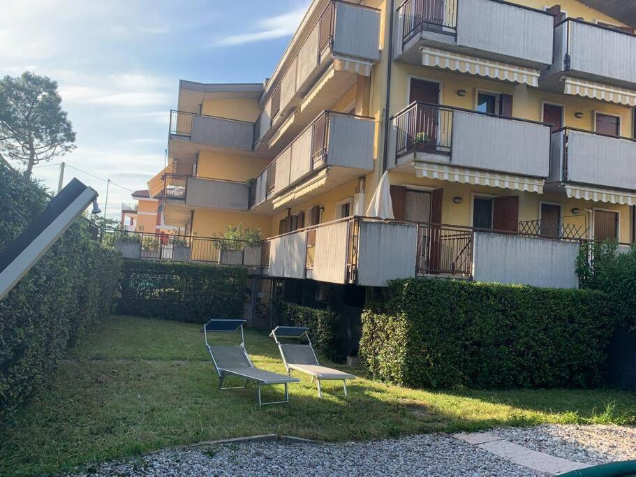 duas cadeiras sentadas na relva em frente a um edifício em Appartamento con piscina e giardino privati em Peschiera del Garda