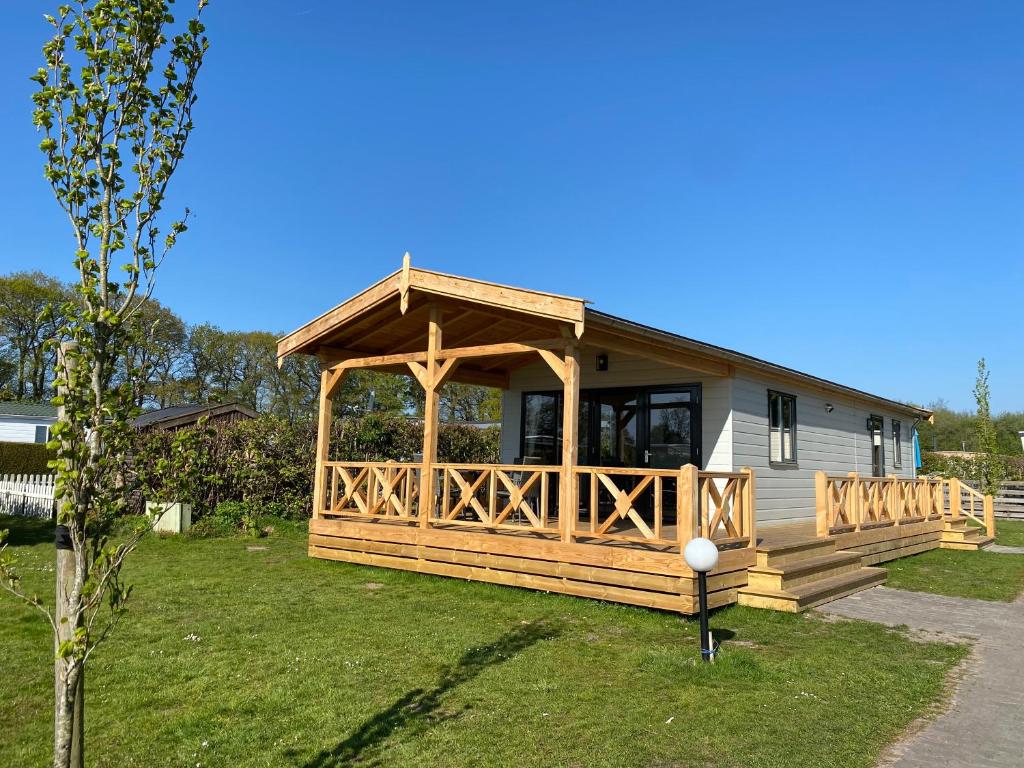 a large wooden cabin with a gazebo at Camping de Ikeleane in Bakkeveen