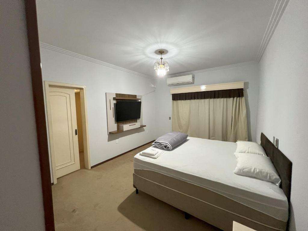 um quarto com uma cama e uma televisão de ecrã plano em Suíte de Luxo no centro, com hidromassagem e closet em Sinop