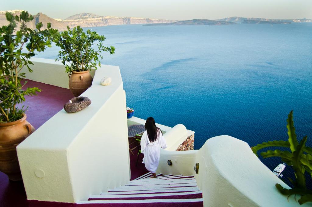 a woman standing on a staircase looking at the water at Angel Cave Houses in Oia