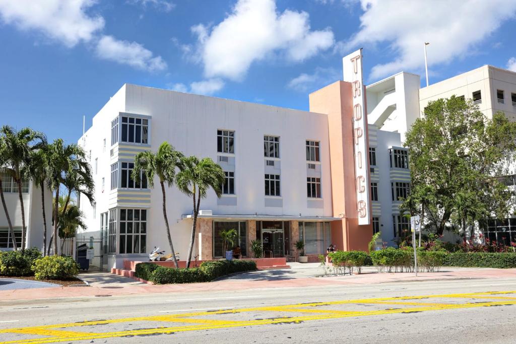 a white building with palm trees in front of a street at Tropics Hotel Miami Beach in Miami Beach