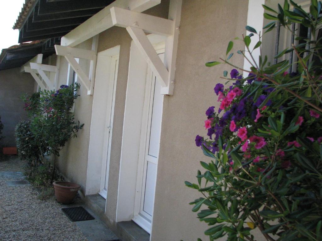 a white door with flowers on the side of a building at Appartements Les Déferlantes Mimizan-plage in Mimizan-Plage