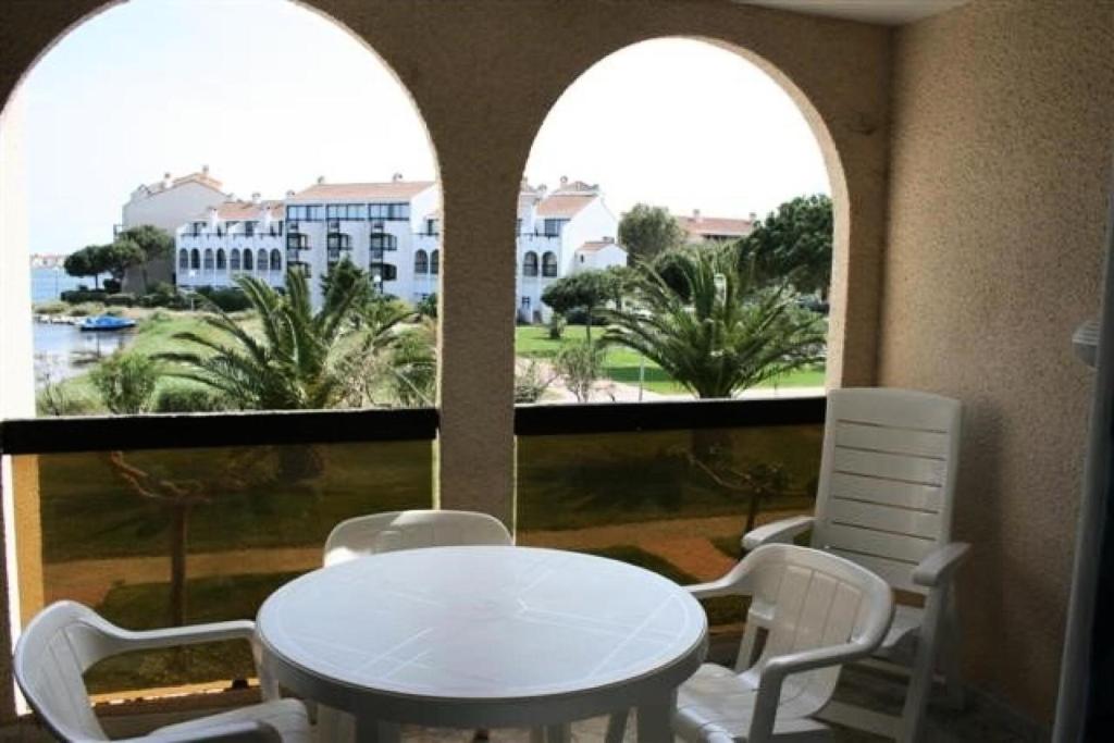 une table et des chaises blanches dans une chambre avec fenêtres dans l'établissement Résidence Caraibes - Appartement 2 pièces au 1er étage à LE BARCARES - CAP COUDALERE MAE-8334, au Barcarès