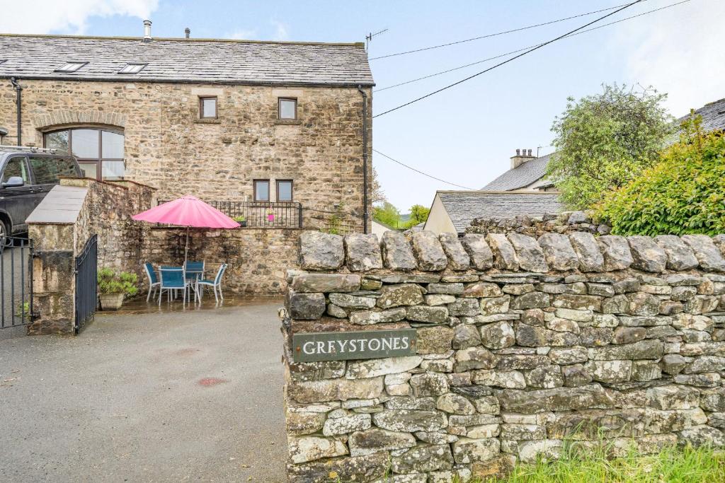 a stone wall with a sign in front of a house at Greystones in Milnthorpe