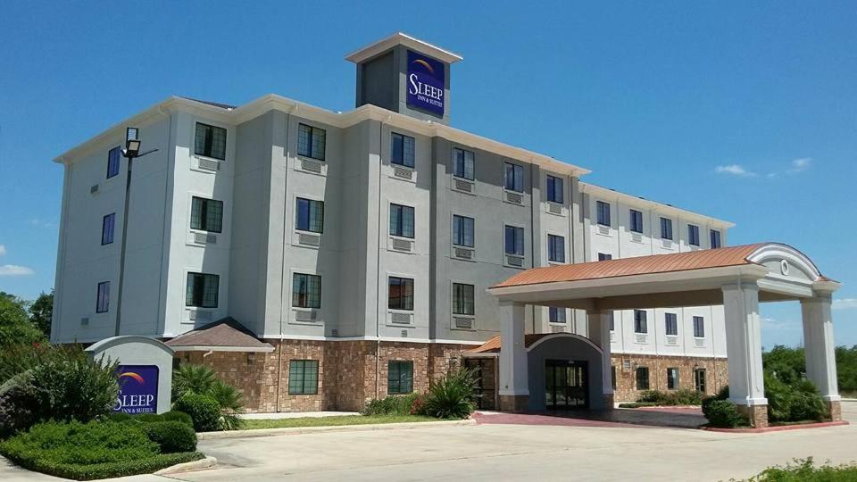 a large white hotel with a sign on top of it at Sleep Inn & Suites at Six Flags in San Antonio