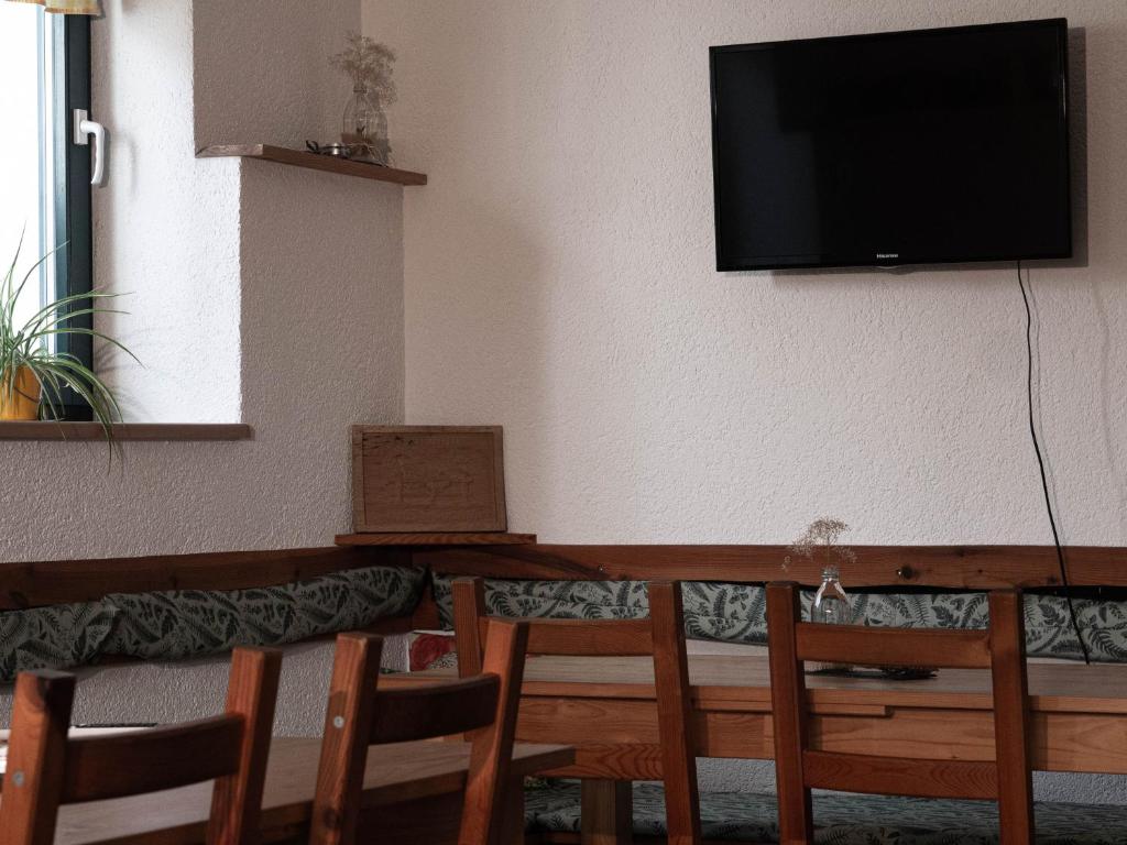 a room with a table with chairs and a television on the wall at Ferienhof Bahlens-Schur in Friedland