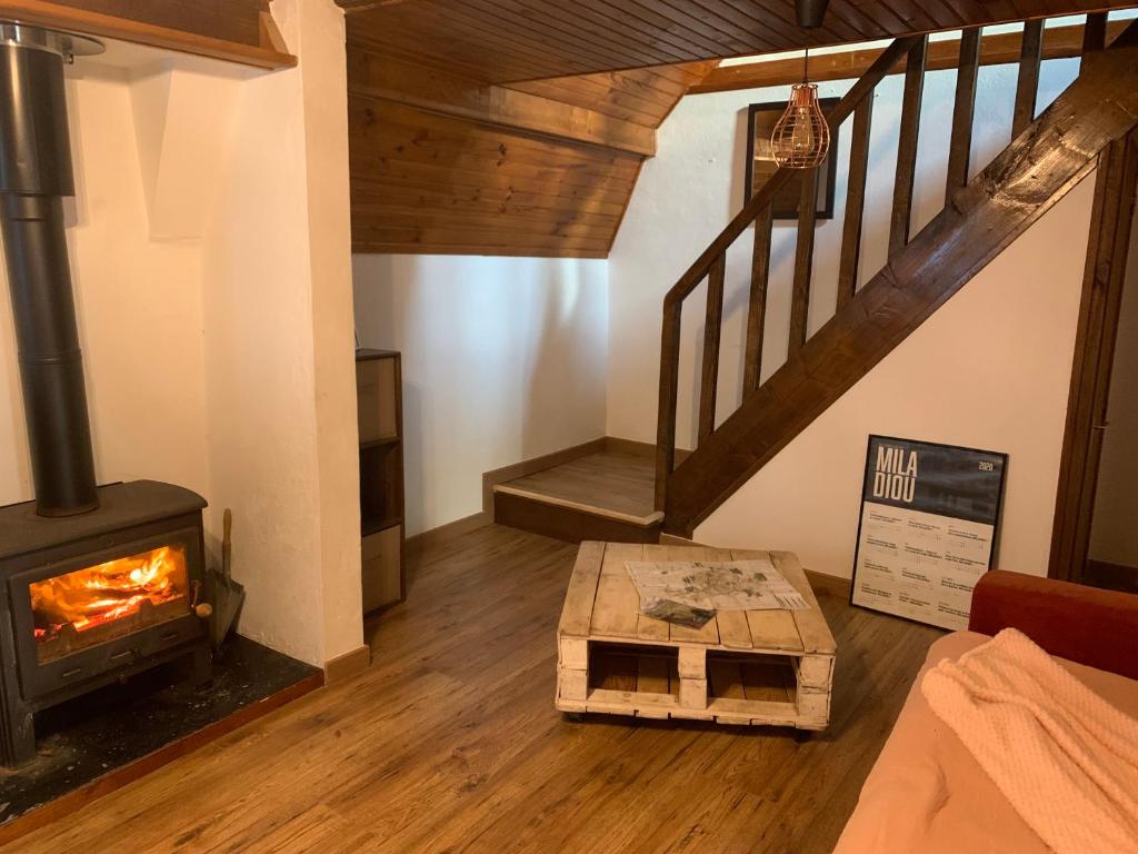 sala de estar con estufa de leña y escaleras en Le Cantou en Castelnau-de-Mandailles