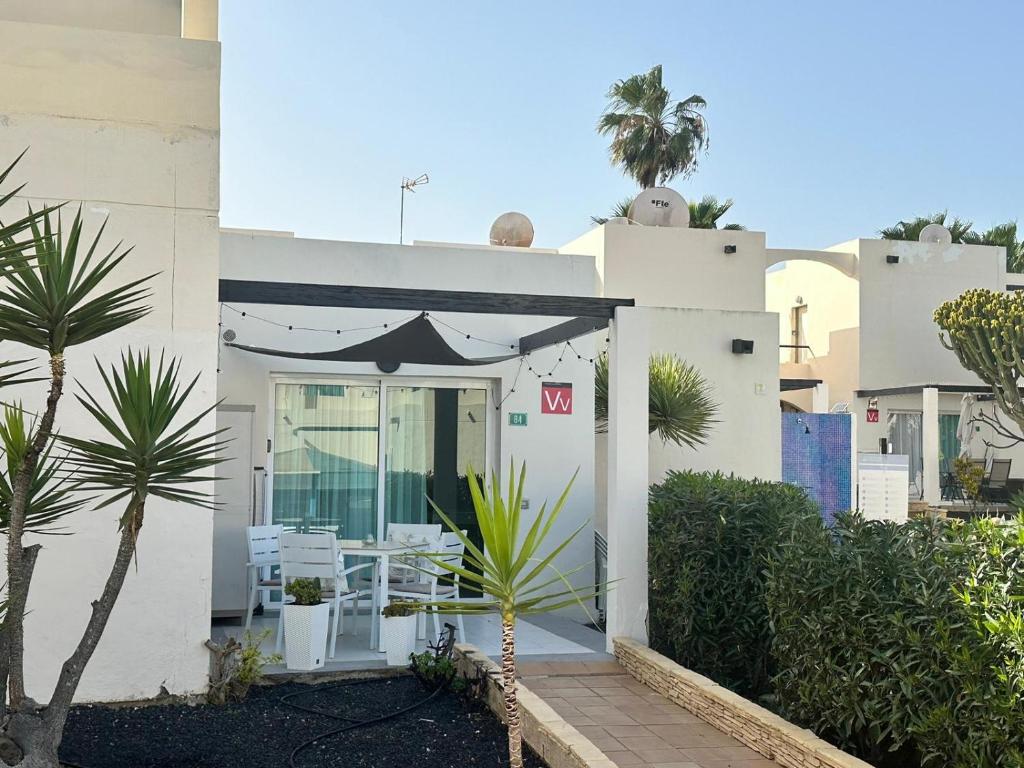 een wit huis met een patio met een tafel en stoelen bij Pachi Beach Alisios Playa Corralejo in Corralejo