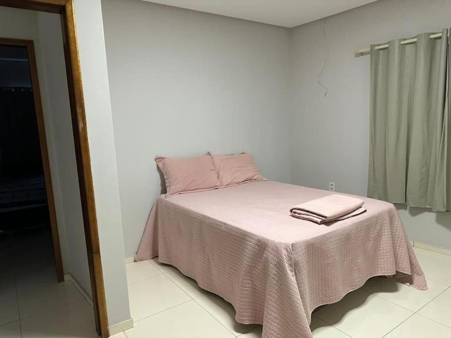 Una cama con sábanas rosas y dos toallas. en Apto apoio Serra da Capivara, en São Raimundo Nonato