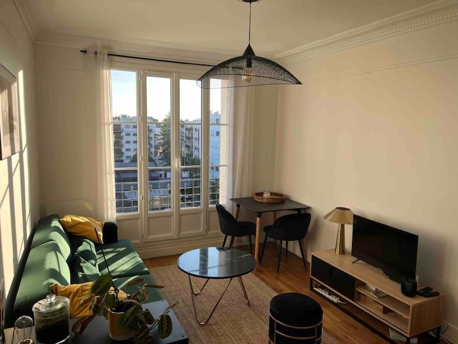 een woonkamer met een bank en een tafel bij Appartement Courbevoie in Courbevoie