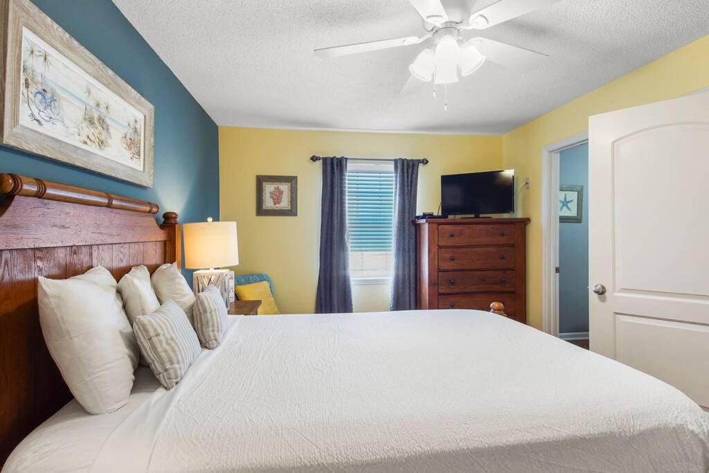 a bedroom with a white bed with a ceiling fan at Lazy Palm Panama City Beach Free New 2023 Golf Cart! Across street From Beach! in Panama City Beach
