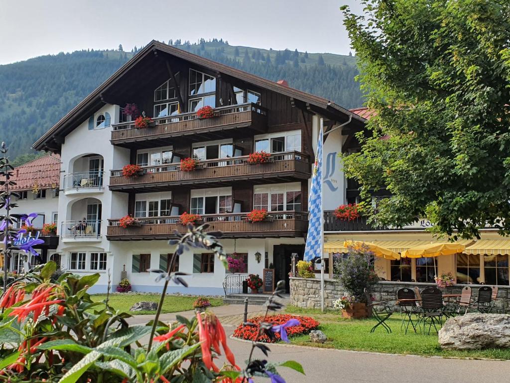 een groot gebouw met bloemen ervoor bij Hotel Alpengasthof Löwen in Bad Hindelang