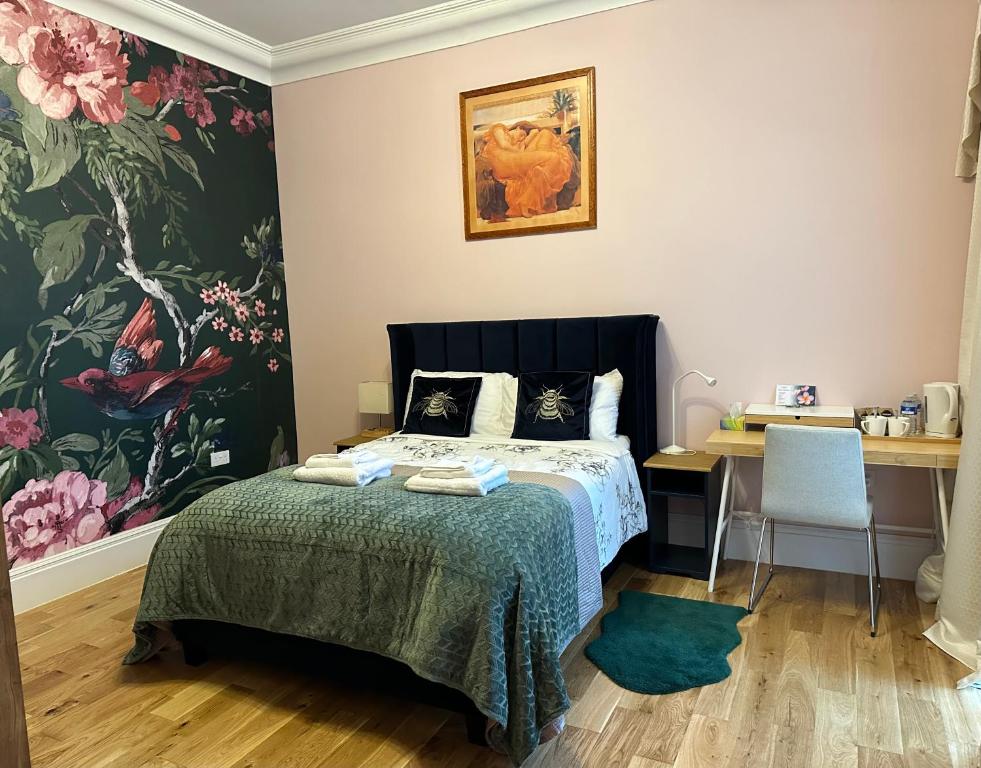 a bedroom with a bed and a desk and a painting at Rosie Cosy House Cricklewood in London