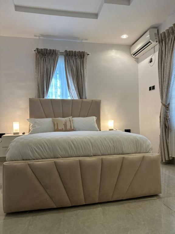 7th Heaven Homes في إيبادان: سرير كبير في غرفة نوم بيضاء مع نافذة