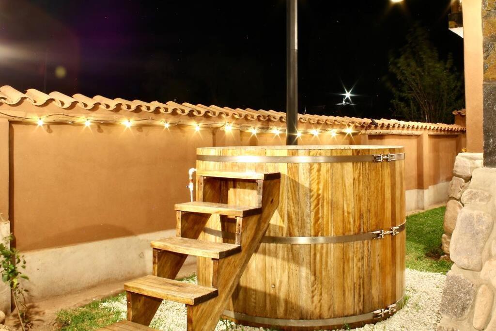a wooden barrel with stairs next to a fence with lights at Hot tub cabin at Sacred Valley in Calca