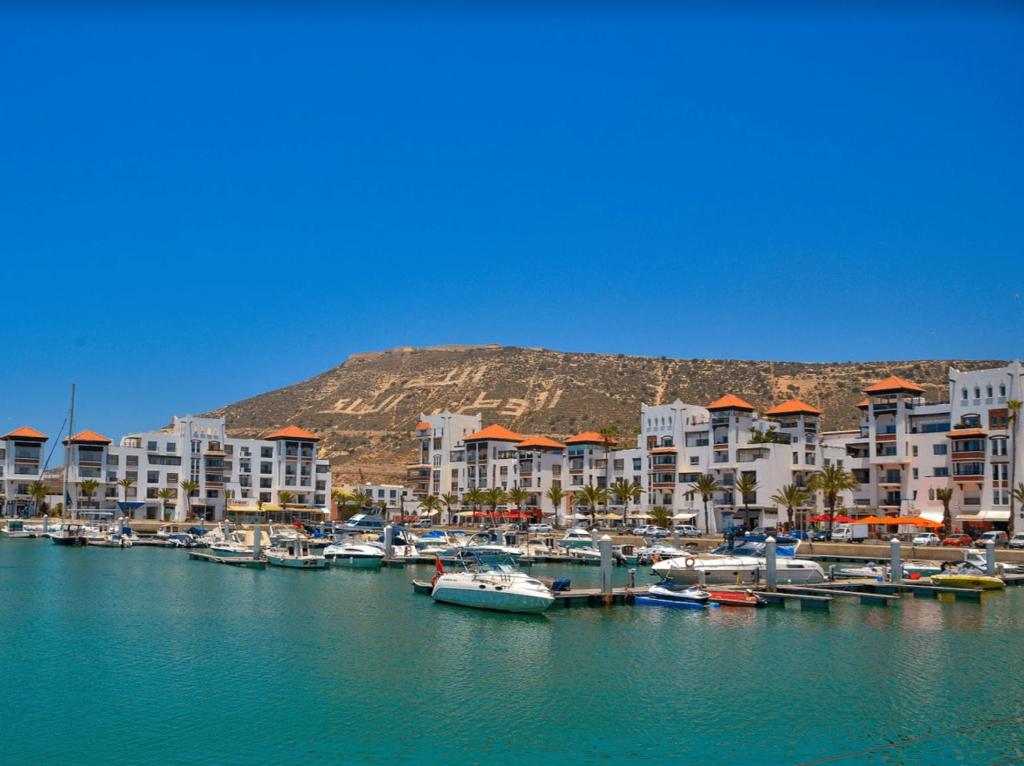 un groupe de bateaux amarrés dans un port avec des bâtiments dans l'établissement Luxueux appartement à la Marina d’agadir, à Agadir