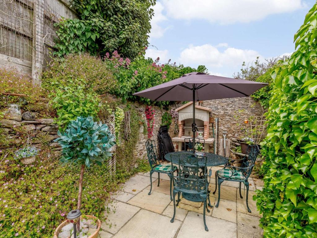 a table and chairs with an umbrella in a garden at 2 bed in Brixham 82723 in Brixham