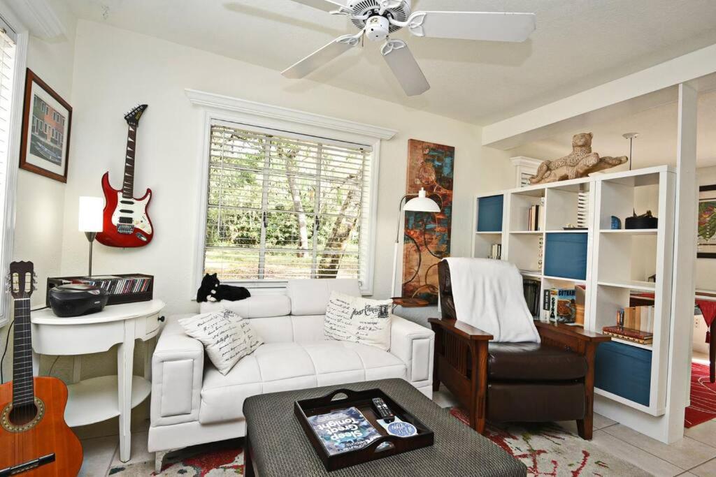 a living room with a white couch and a guitar at Quaint Winter Park East End Home in Orlando