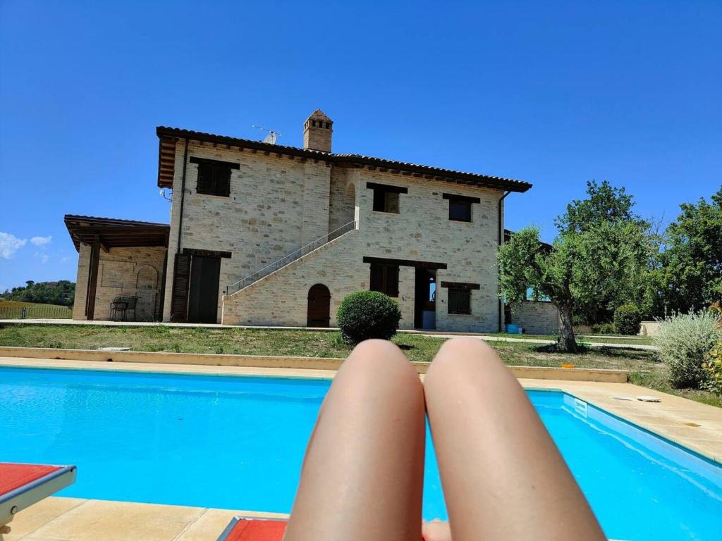 una persona con le gambe in aria accanto a una piscina di fronte di 5 bedrooms house with private pool terrace and wifi at Ripatransone a Cossignano