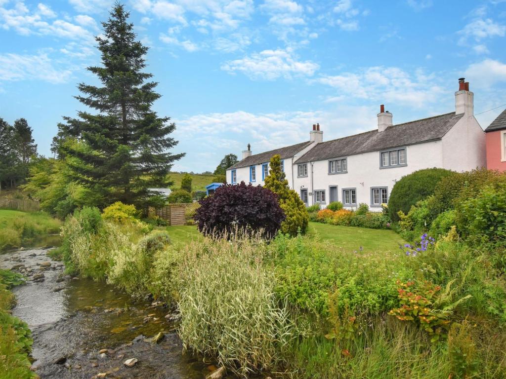 a house with a stream in front of it at 3 Bed in Caldbeck 86087 in Caldbeck