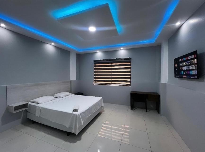 una camera da letto con un letto e una luce blu sul soffitto di Hotel KP a Portoviejo