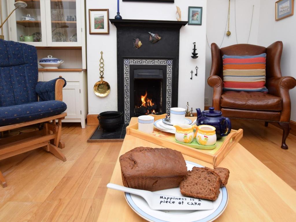 un salon avec une table avec du pain et une cheminée dans l'établissement 2 bed property in Findochty 76557, à Findochty