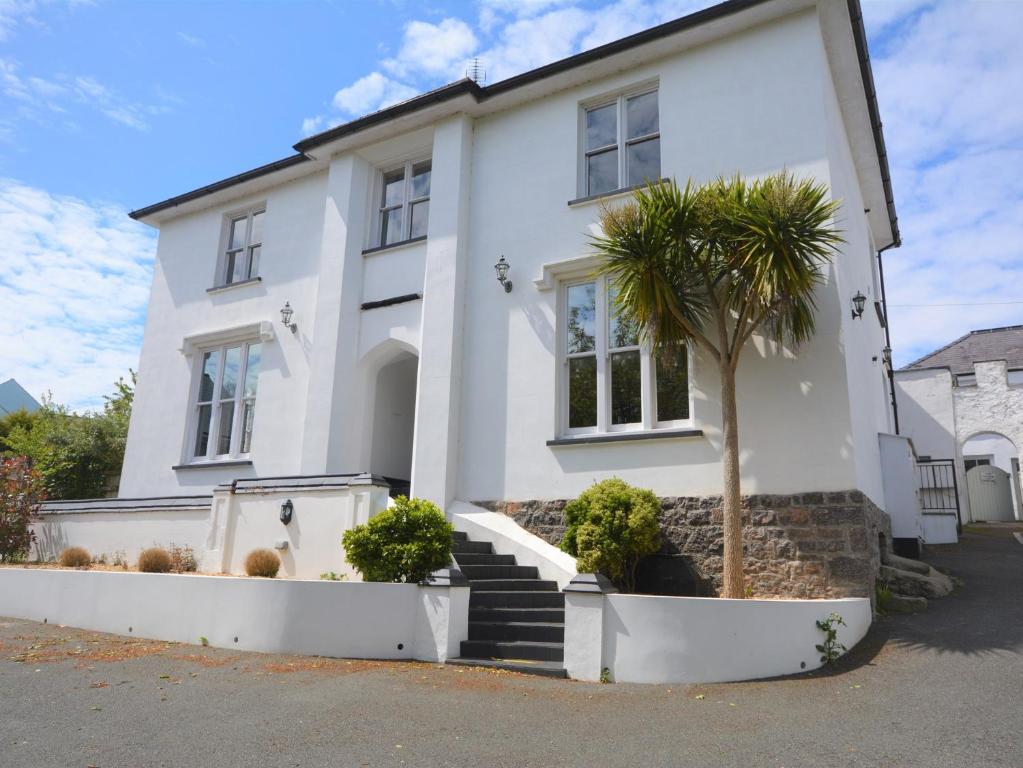 a white house with a palm tree in front of it at 3 Bed in Tenby 73606 in Tenby