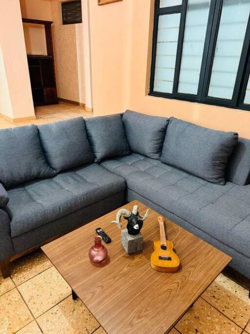 un sofá azul con dos guitarras en una mesa de centro en Departamento La Comarca 2, en Tepatitlán de Morelos