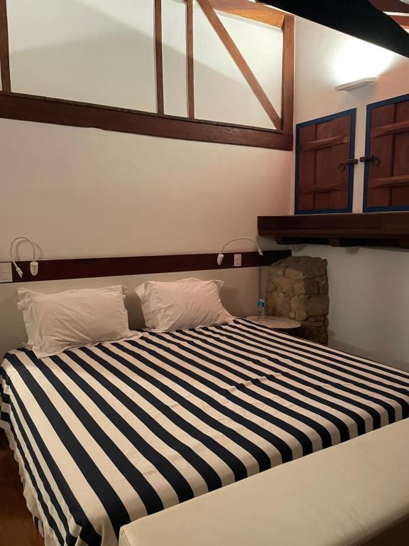 a bedroom with a large bed with black and white stripes at Casa centro histórico Paraty in Paraty