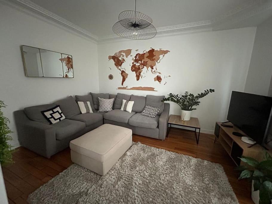 uma sala de estar com um sofá e um mapa do mundo na parede em Proche de Paris - 3 minutes du métro em Levallois-Perret