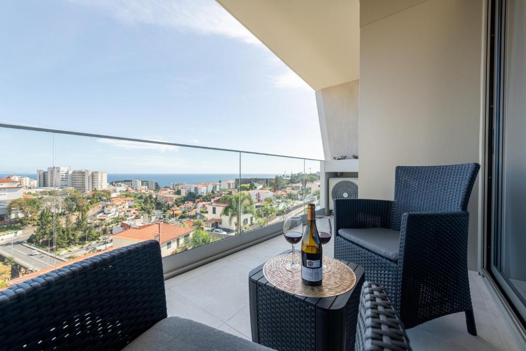 een kamer met 2 stoelen en een tafel met een fles wijn bij The King Apartment in Santo António