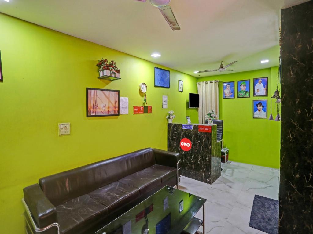 una sala de espera con un sofá de cuero en una pared verde en OYO Flagship 81337 New Gour Plaza en Nueva Delhi