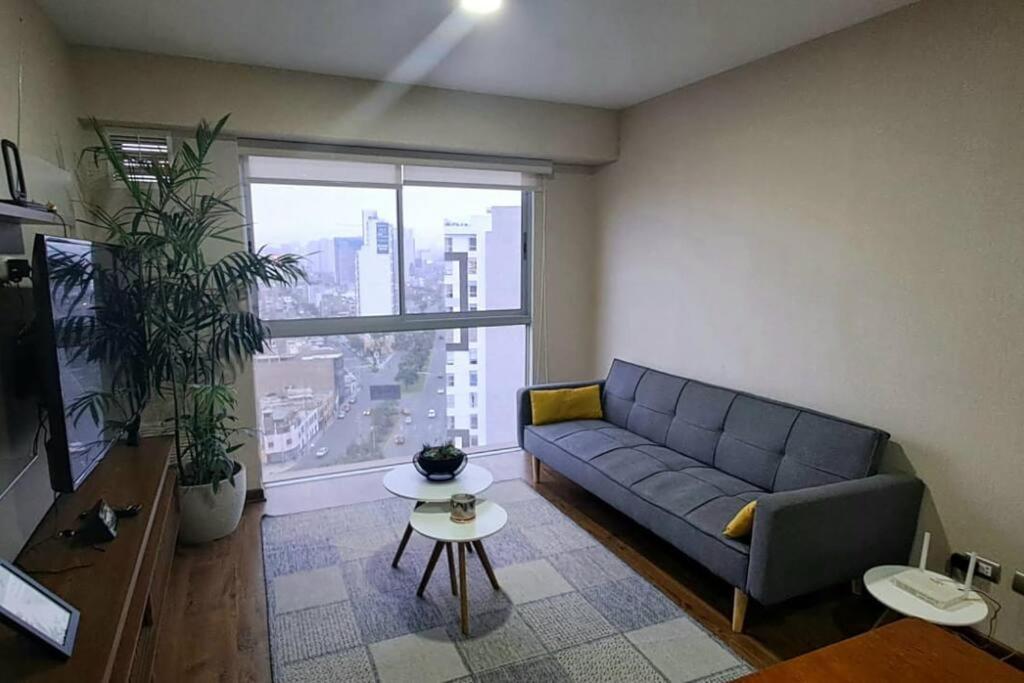 sala de estar con sofá azul y ventana grande en Comodidad y vista impresionante, en Lima