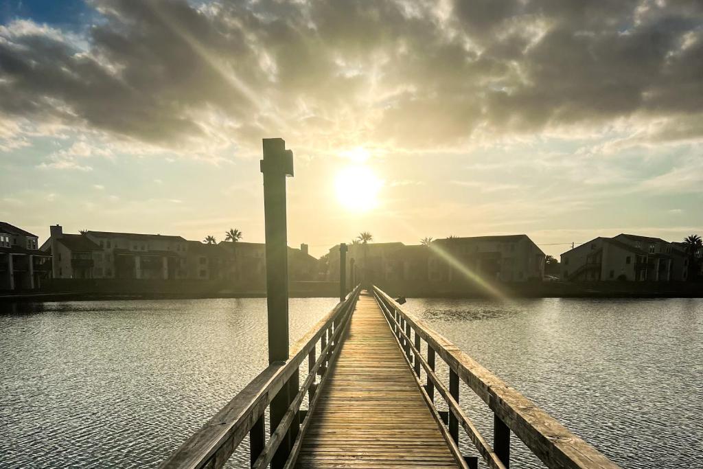 Un puente de madera sobre un cuerpo de agua con el sol. en Rockport Getaway #608, en Rockport