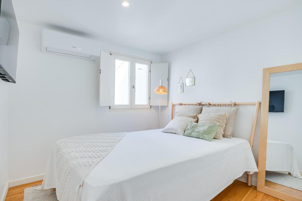 um quarto branco com uma cama branca e um espelho em Largo Inn Suites Evora em Évora