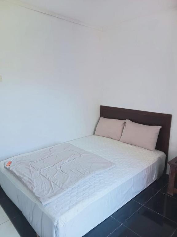 a bed with white sheets and pink pillows on it at Ya Bunayya Villa in Sembalun Lawang