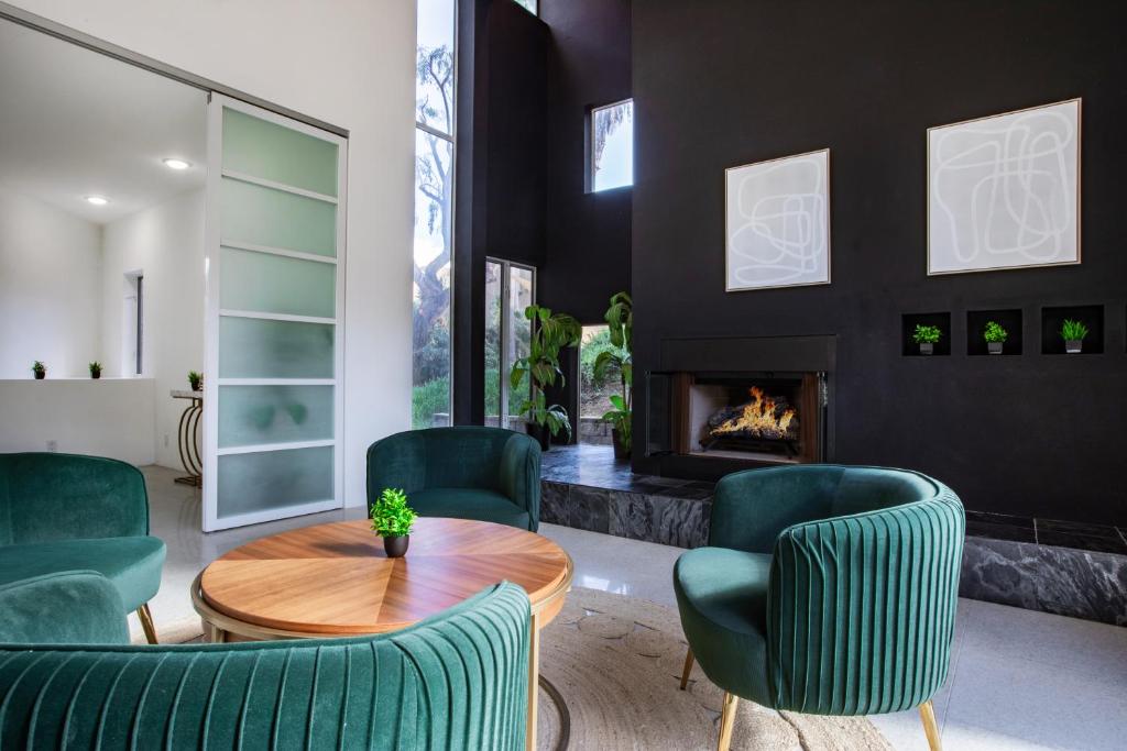 a living room with green chairs and a table and a fireplace at Elite Retreat! Hot Tub, Arcade, & Theater. 6 Beds! in Encinitas