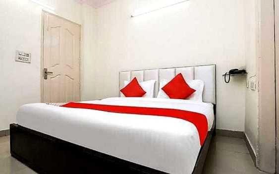sypialnia z dużym białym łóżkiem z czerwonymi poduszkami w obiekcie OYO Hotel Kamal w mieście Bharatpur