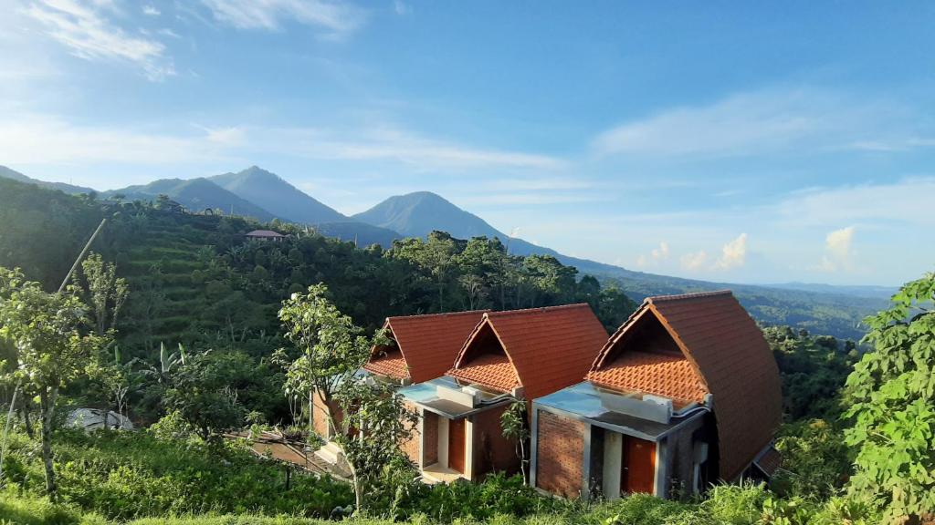 a house on a hill with mountains in the background at Camaradvipa Retreat Munduk in Munduk