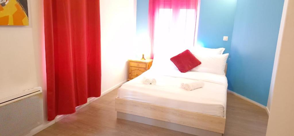 a small room with a bed with red curtains at Hôtel Le Saint Quentin in Saint-Quentin