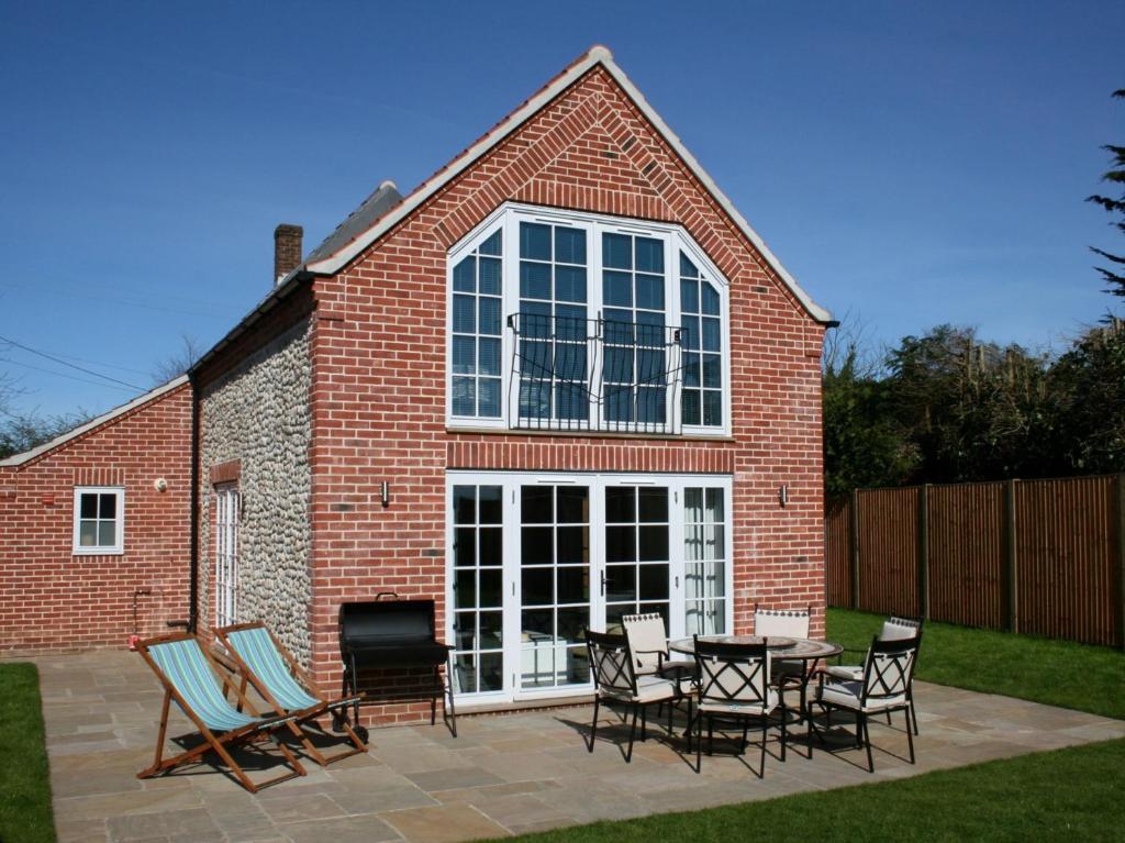 a brick building with a patio with chairs and a table at 3 Bed in Cromer 47832 in Northrepps