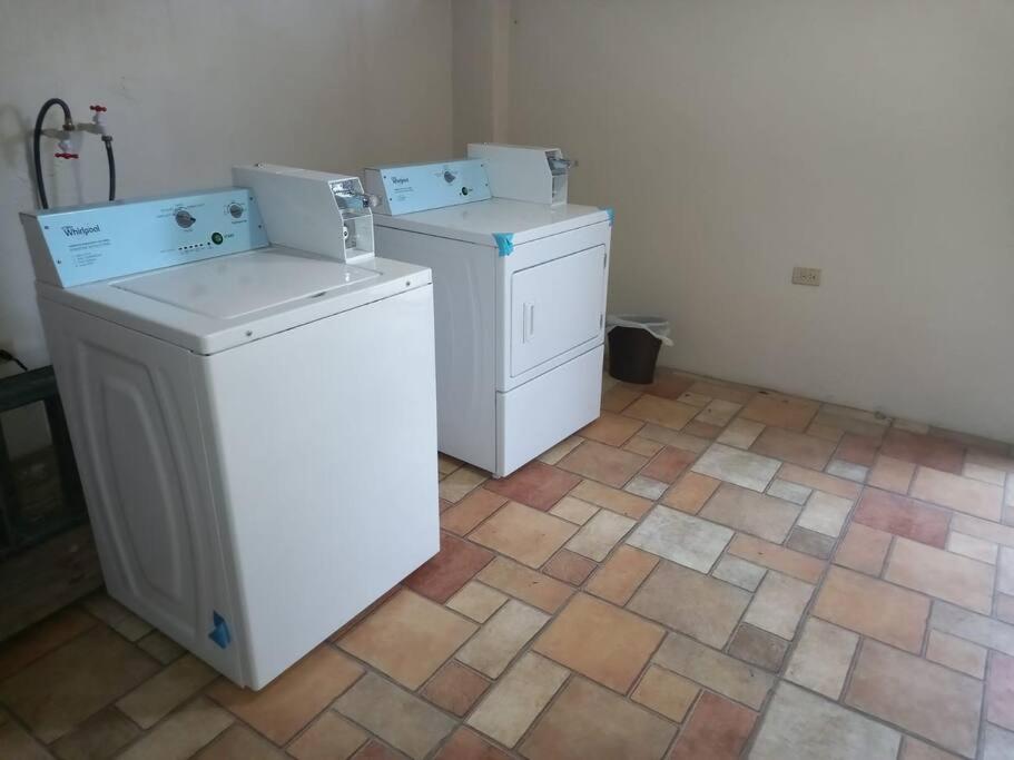 Habitación con suelo de baldosa y 2 lavadoras y secadoras. en Close to Everything, en Puerto España