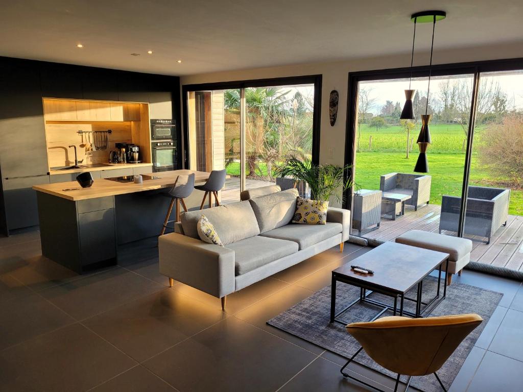 uma sala de estar com um sofá e uma cozinha em Villa en bois à la campagne - 20 min de Rouen em Morgny-la-Pommeraye